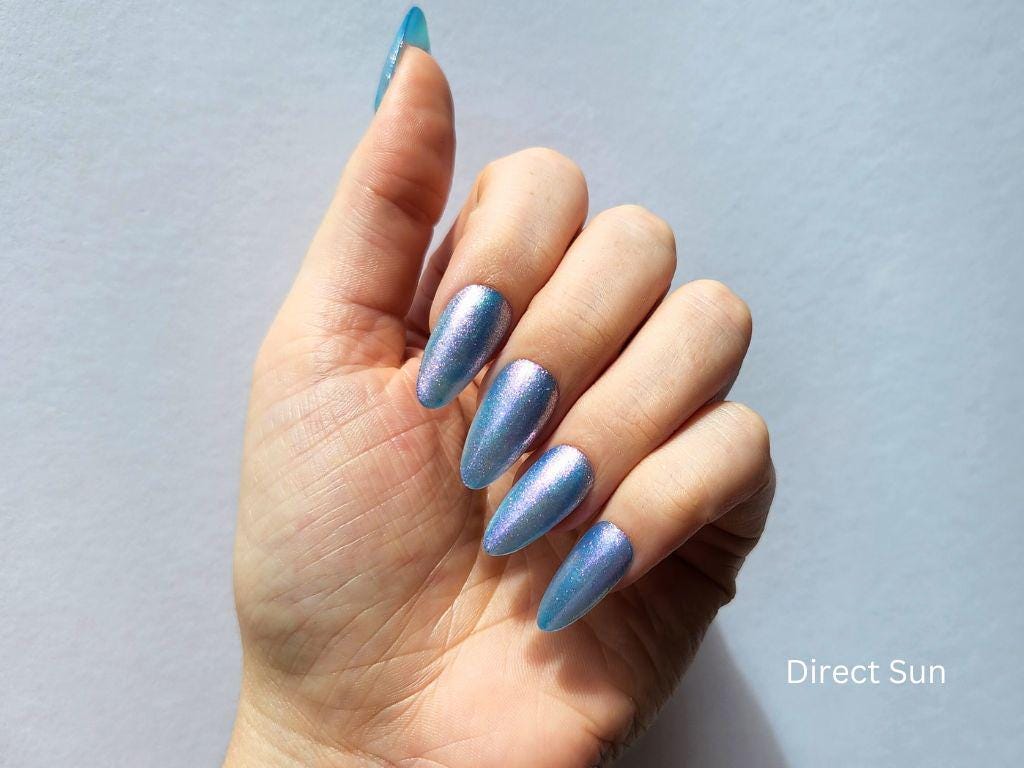 Glow & Tell swatch on light skin – sheer blue nail polish with purple shimmer