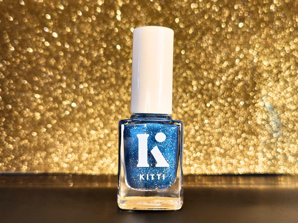 Vegan gold glitter nail polish in rich blue base – bottle photo