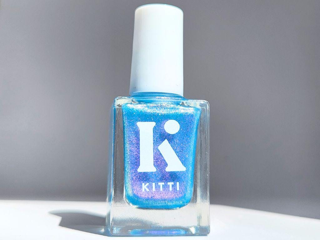 Bottle of Glow & Tell – sheer blue nail polish with vibrant purple shimmer