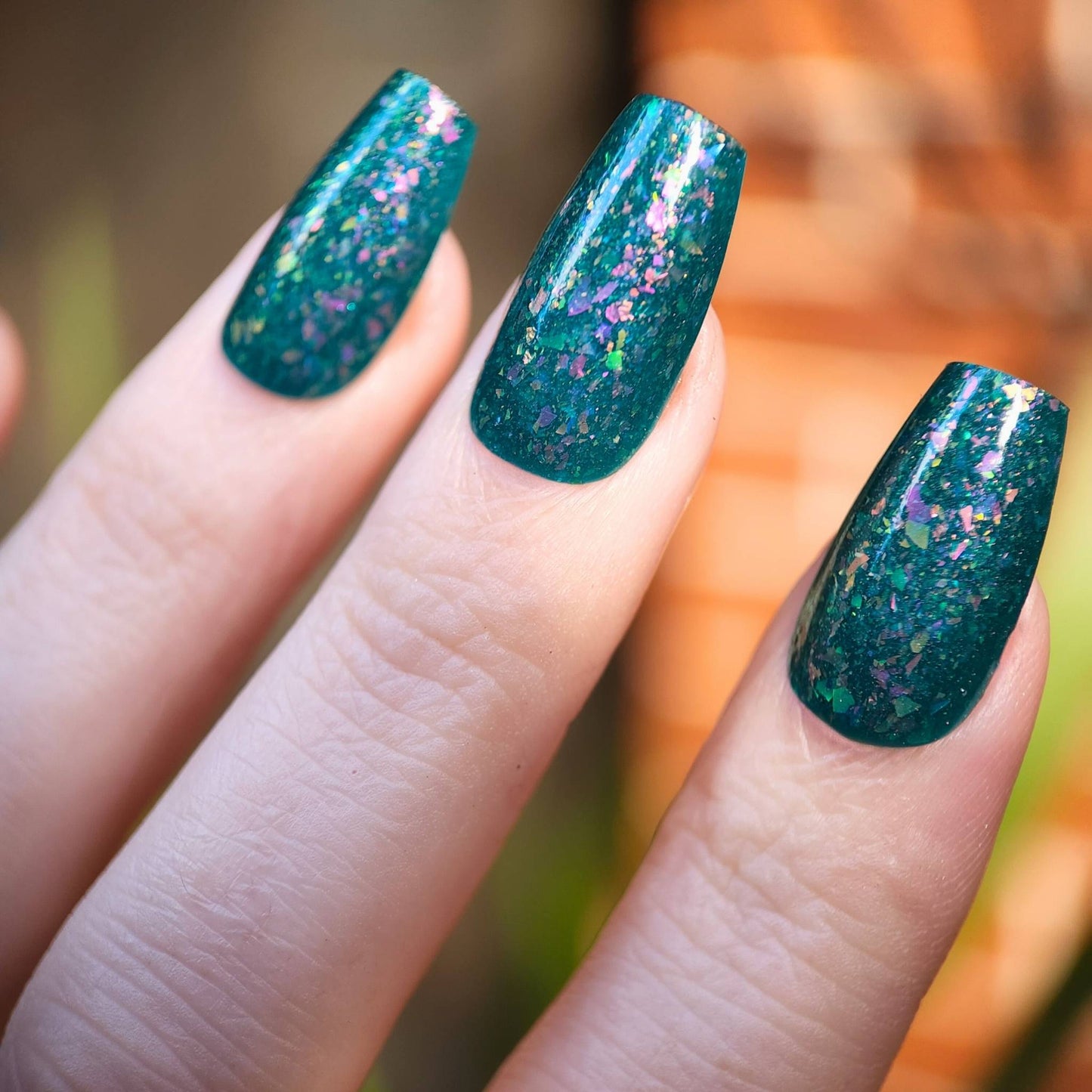Teal jelly nail polish with sparkly iridescent flakes