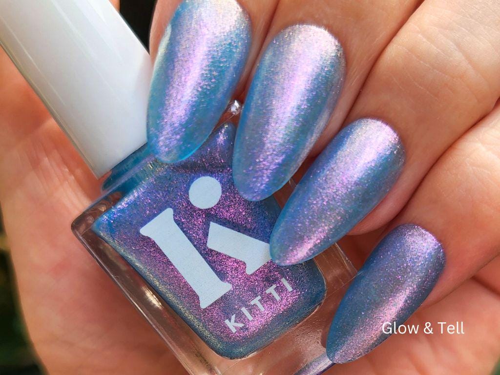 Bottle of Glow & Tell – sheer blue nail polish with vibrant purple shimmer