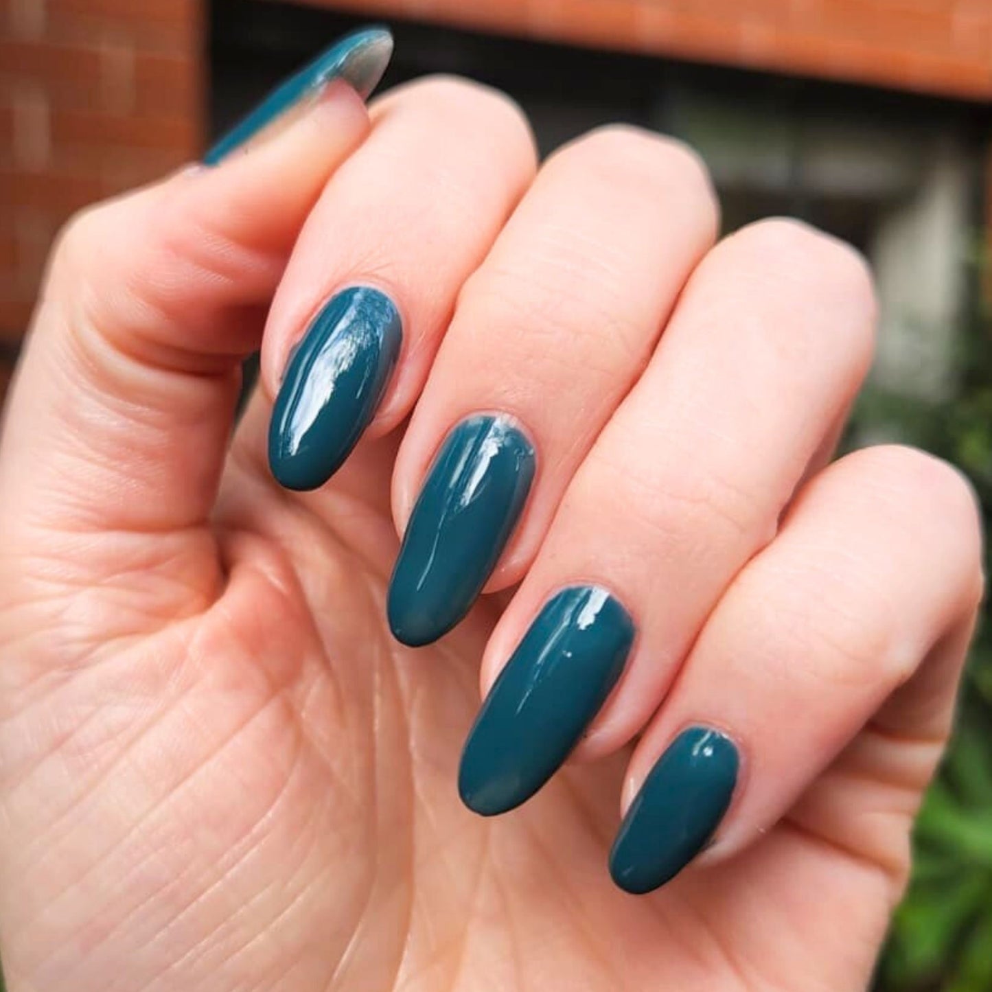 Hand with teal nail polish against a blurred background