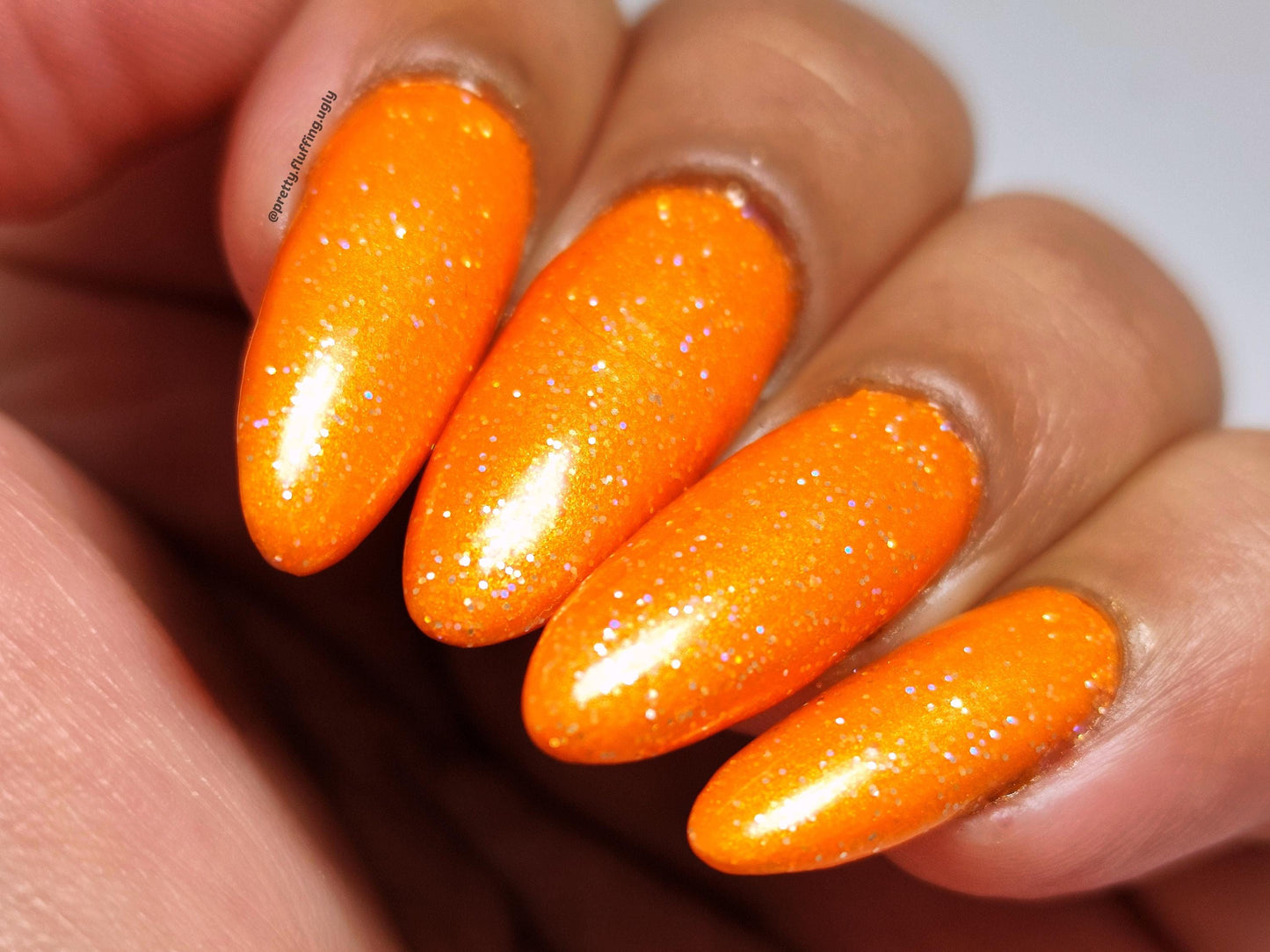 Full coverage orange glitter polish – swatched on deep skin tone