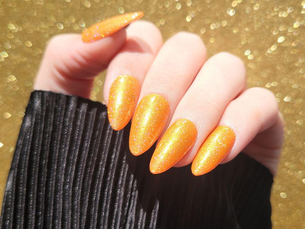 Swatch of bright orange holographic nail polish on light skin – full coverage, vegan and cruelty-free