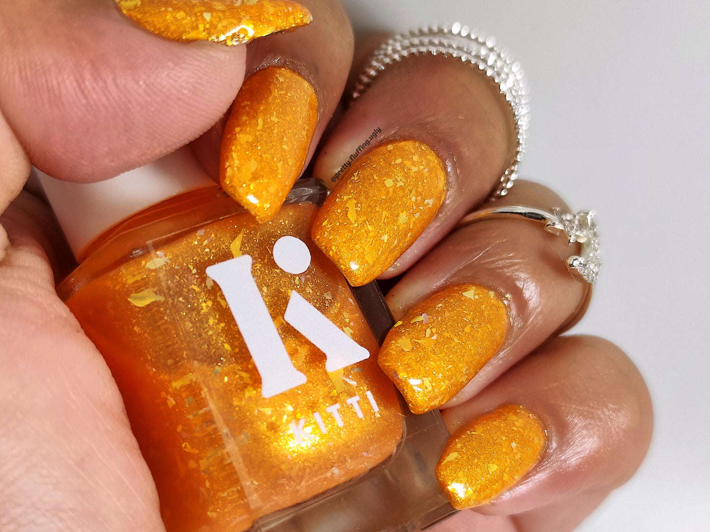 Orange and gold flake polish on dark skin tone – glowing summer nails