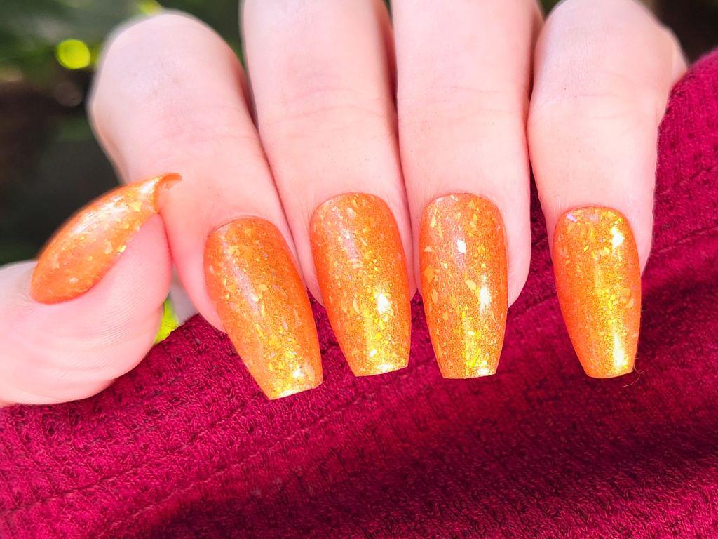Orange jelly nail polish with gold shimmer on light skin – Here Comes the Sun