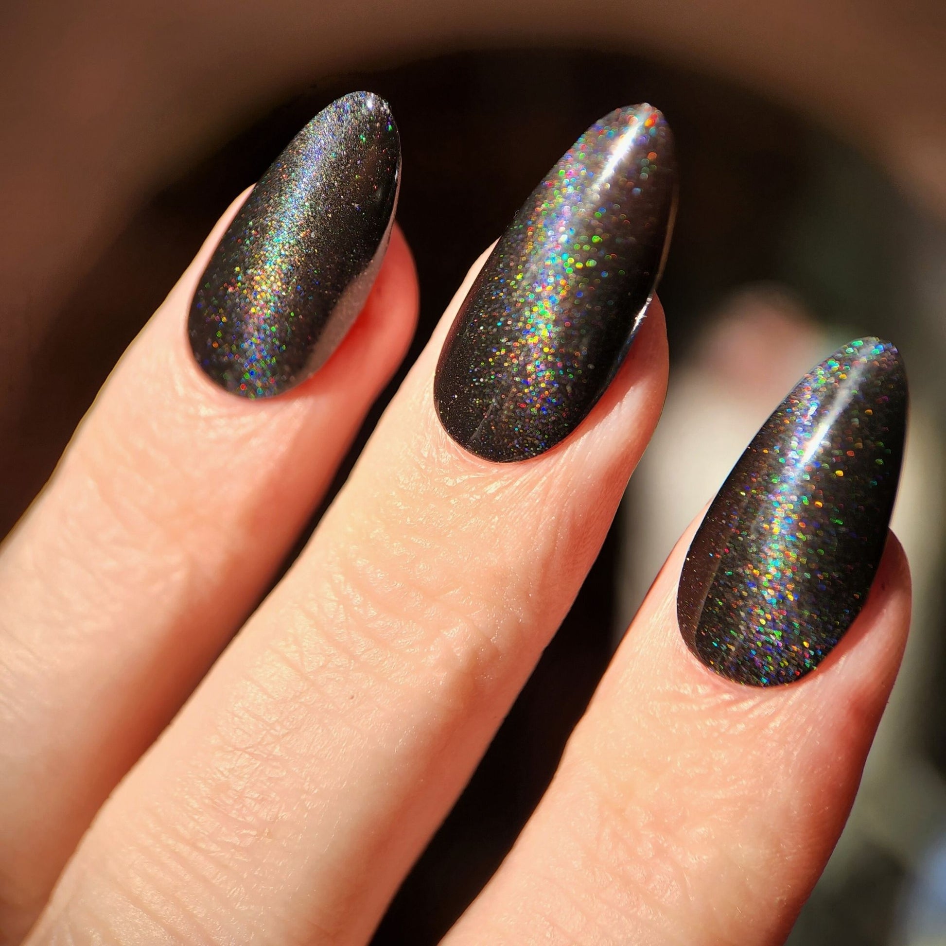 Swatch of black cat eye magnetic nail polish with rainbow shimmer