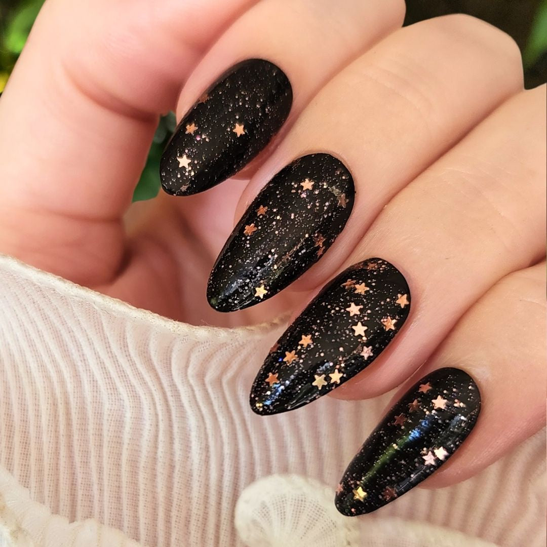 Champagne Popper glitter topper over Black Out black nail polish showing rose gold stars and sparkling glitter