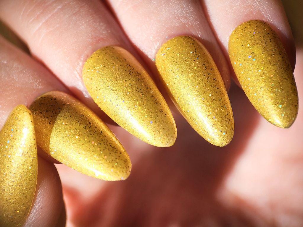 Macro of gold holographic glitter in yellow polish – indie, quick-drying formula