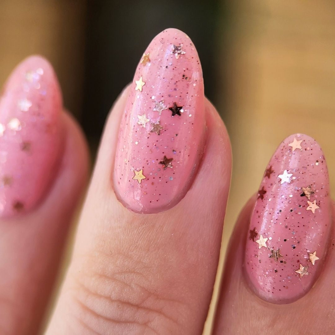 Champagne Popper glitter topper swatched over Romantic Delusion pink nail polish with rose gold star confetti