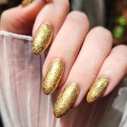 Close-up of hands with gold glittery christmas nail polish on a blurred background