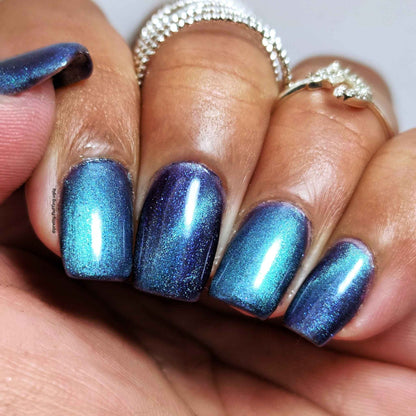 Close-up of a nail polish swatch on dark skin tone magnetic green and purple nail polish in cat eye and velvet style 