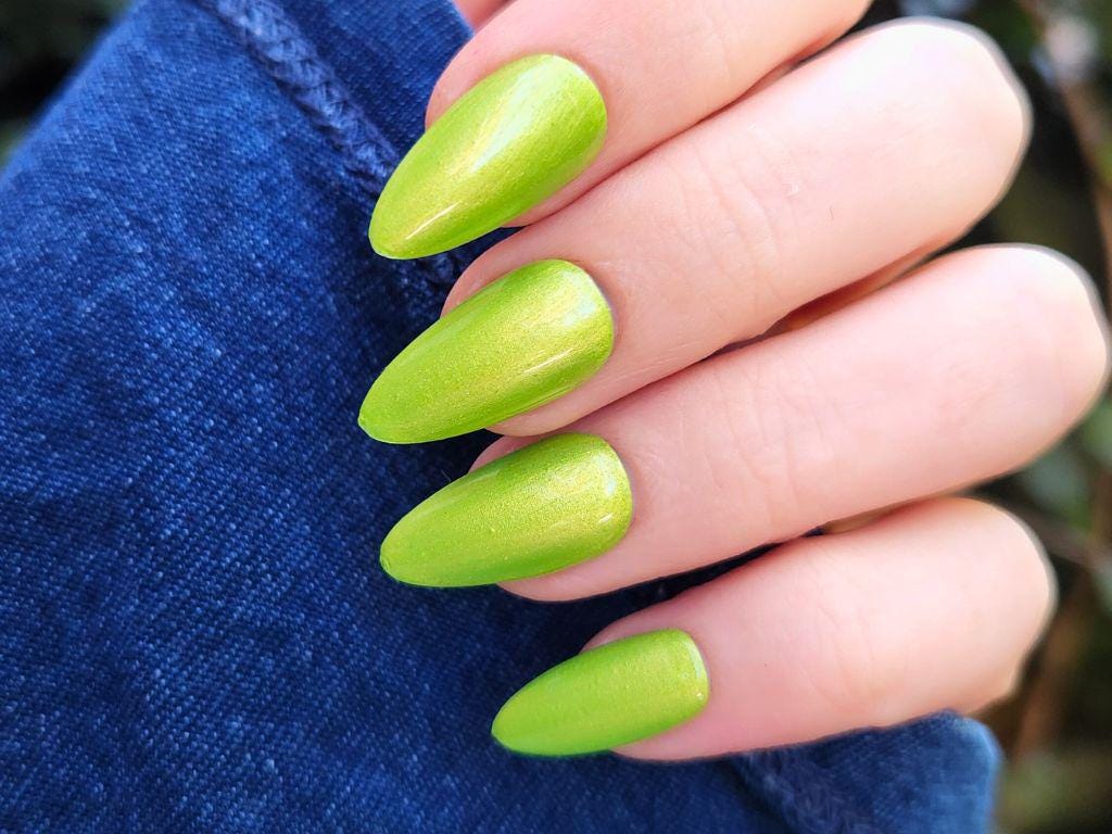 Brat green nail polish swatch on light skin – gold shimmer finish