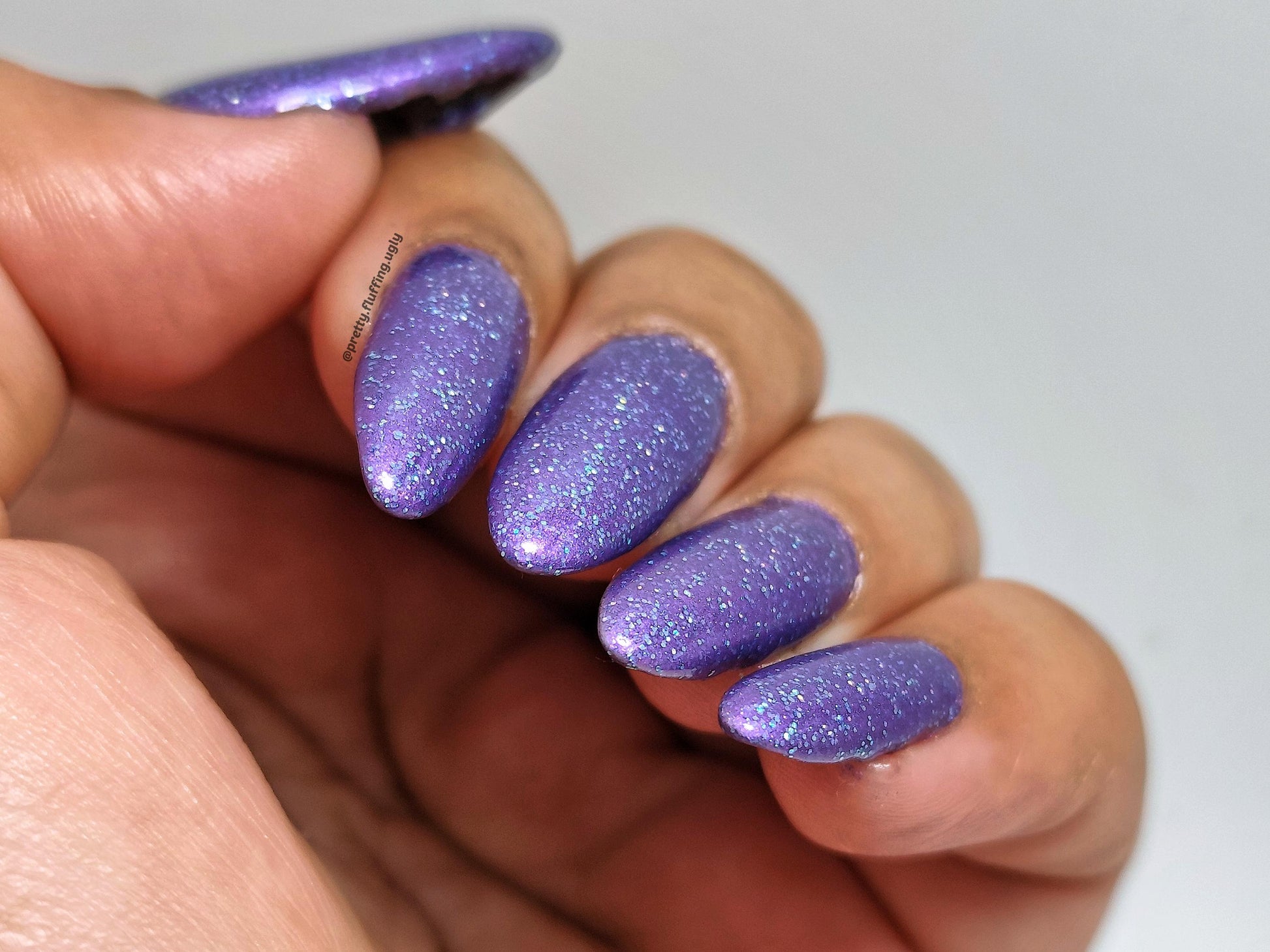 Moody purple shimmer polish on deep skin tone – holographic sparkle swatch